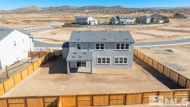 back of property with a fenced backyard and a mountain view