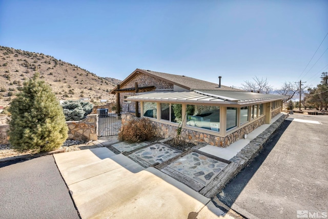 view of front of house featuring a gate, a standing seam roof, metal roof, fence, and stone siding