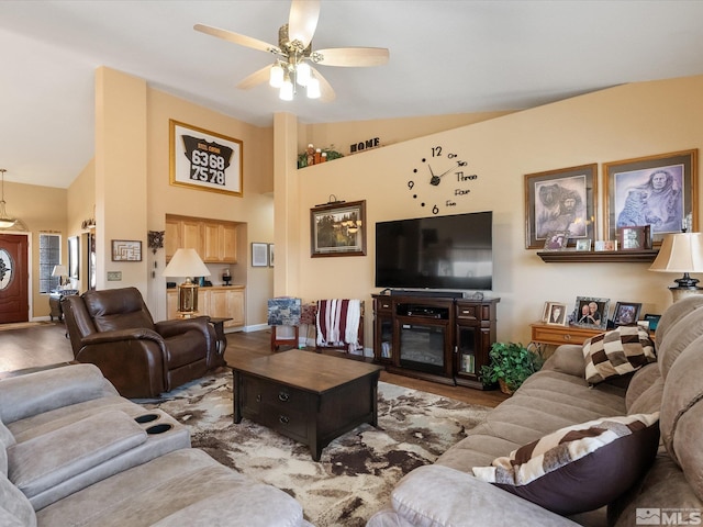 living area featuring baseboards, ceiling fan, high vaulted ceiling, and wood finished floors