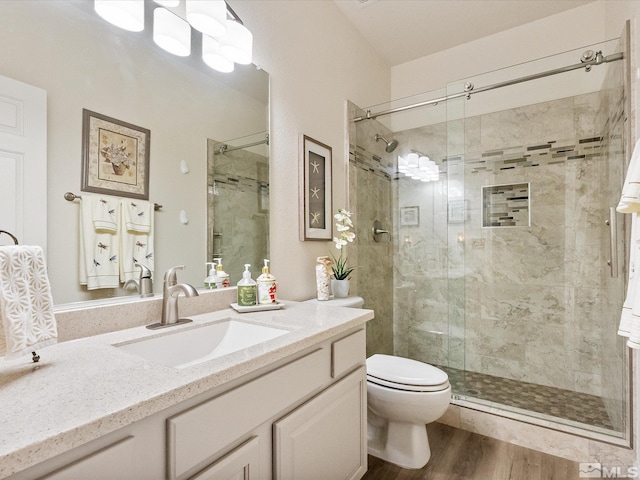 full bath with vanity, a shower stall, toilet, and wood finished floors