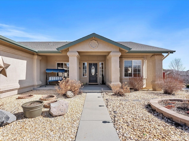 entrance to property with roof with shingles and stucco siding