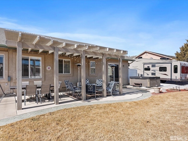 back of house featuring stucco siding, a lawn, a hot tub, a patio area, and a pergola