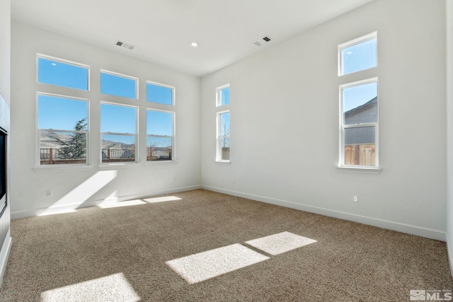 spare room with carpet, visible vents, and baseboards