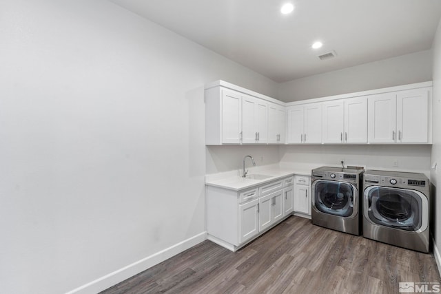 clothes washing area with a sink, visible vents, baseboards, washer and dryer, and dark wood-style floors