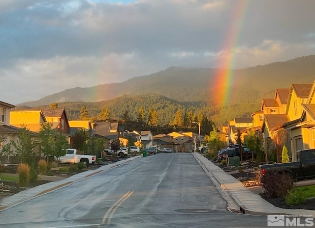 view of road with sidewalks, a residential view, a mountain view, and curbs