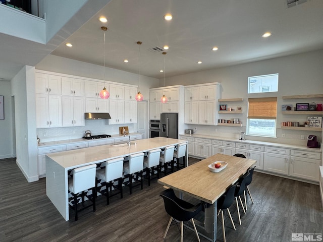 kitchen with white cabinets, under cabinet range hood, stainless steel appliances, and open shelves