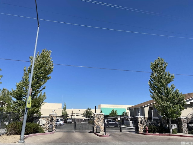 view of street featuring a gate, a gated entry, and curbs