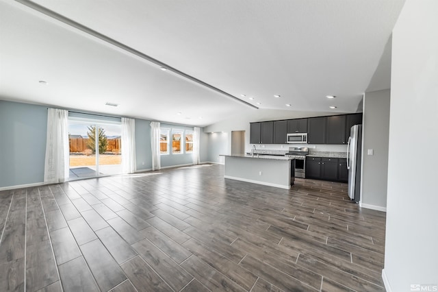 unfurnished living room featuring lofted ceiling, a sink, visible vents, baseboards, and wood tiled floor