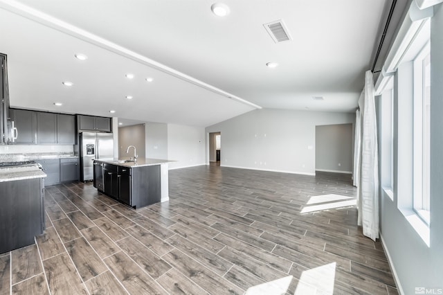 kitchen featuring wood tiled floor, open floor plan, visible vents, and stainless steel refrigerator with ice dispenser