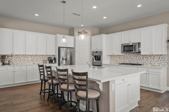 kitchen with dark wood-type flooring, visible vents, stainless steel appliances, and a sink