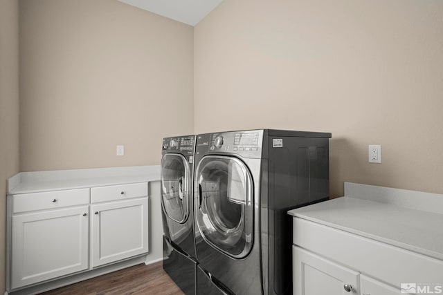 laundry room featuring cabinet space, dark wood finished floors, and washing machine and clothes dryer