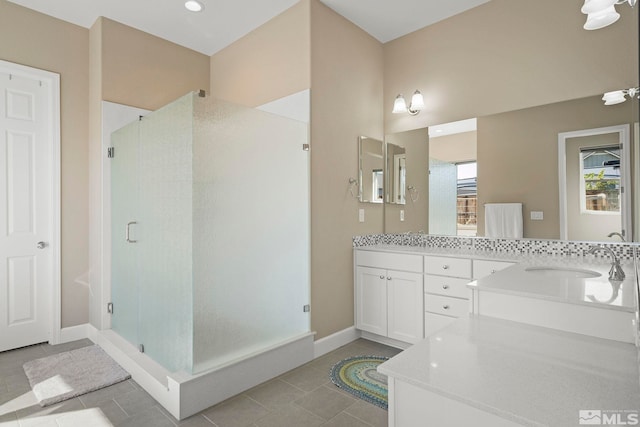 bathroom featuring a wealth of natural light, a stall shower, a sink, and double vanity