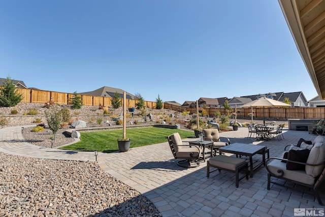 view of patio featuring outdoor dining area, a fenced backyard, and a residential view