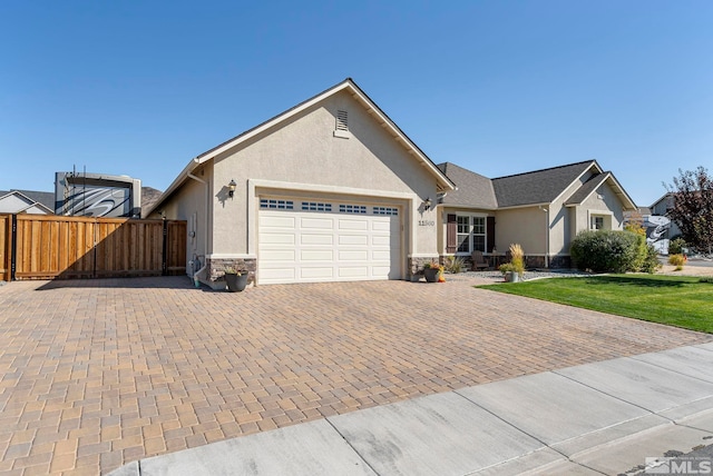 single story home featuring an attached garage, fence, stone siding, decorative driveway, and stucco siding