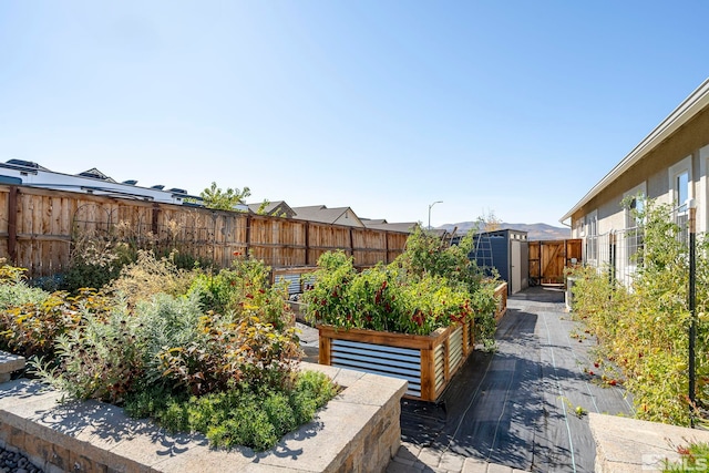 view of yard with a vegetable garden, a fenced backyard, a shed, and an outbuilding