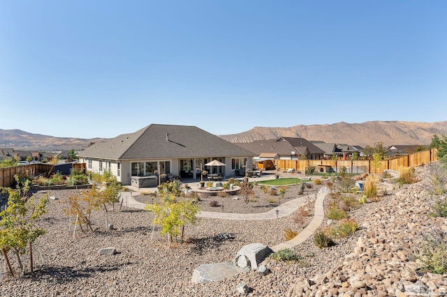 back of house featuring a fenced backyard, a mountain view, and a patio