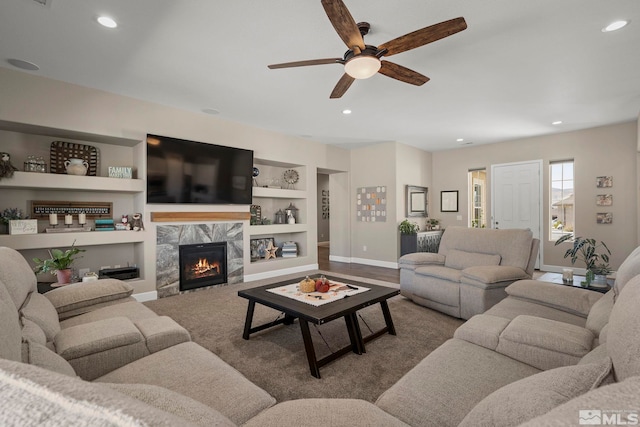 living area featuring baseboards, recessed lighting, a high end fireplace, and built in features