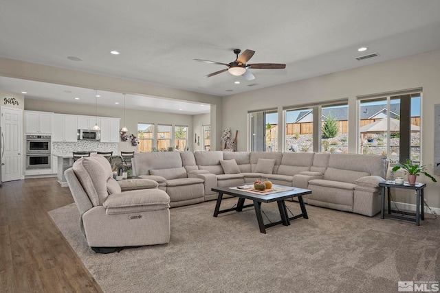 living area with ceiling fan, dark wood-type flooring, plenty of natural light, and visible vents