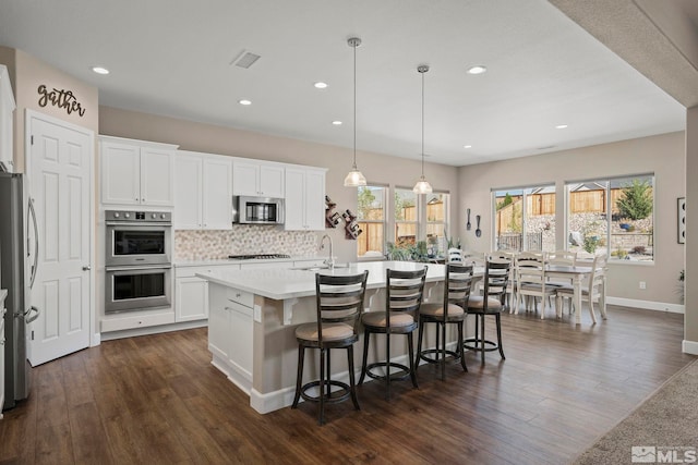 kitchen with stainless steel appliances, dark wood-type flooring, a sink, and visible vents