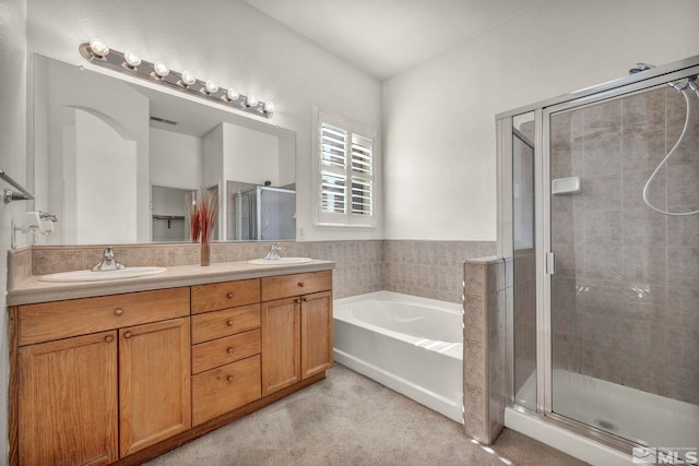 bathroom featuring a garden tub, double vanity, a sink, and a shower stall