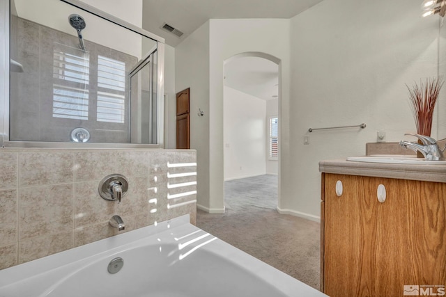 bathroom with visible vents, a shower with shower door, vanity, baseboards, and a bath