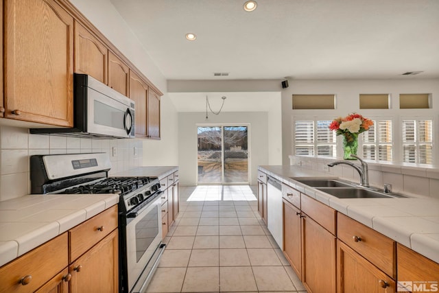 kitchen with visible vents, decorative backsplash, tile countertops, stainless steel appliances, and a sink