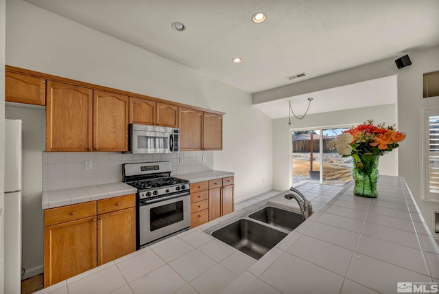 kitchen featuring visible vents, tile counters, appliances with stainless steel finishes, backsplash, and a sink