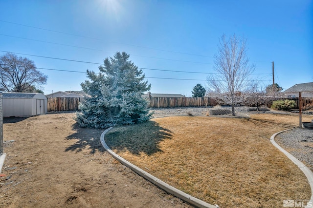 view of yard with a fenced backyard, a storage unit, and an outbuilding