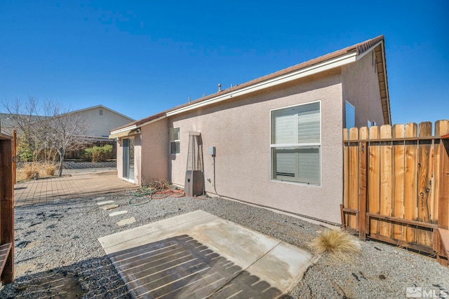 rear view of property featuring a patio area, fence, and stucco siding