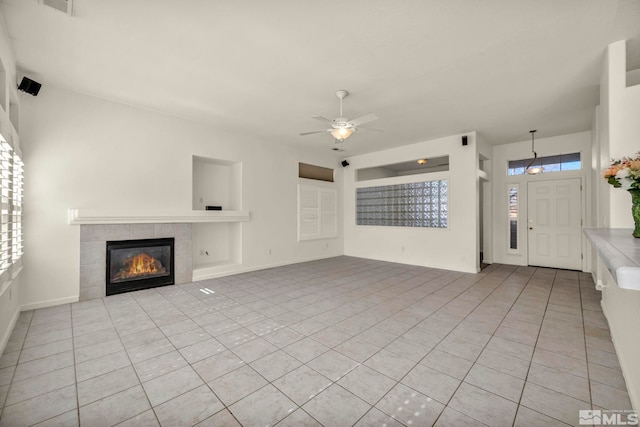 unfurnished living room with a ceiling fan, light tile patterned flooring, and a tiled fireplace