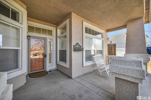 view of exterior entry featuring a porch and stucco siding