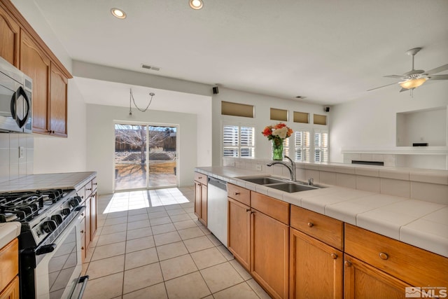 kitchen with tile counters, appliances with stainless steel finishes, a sink, and visible vents