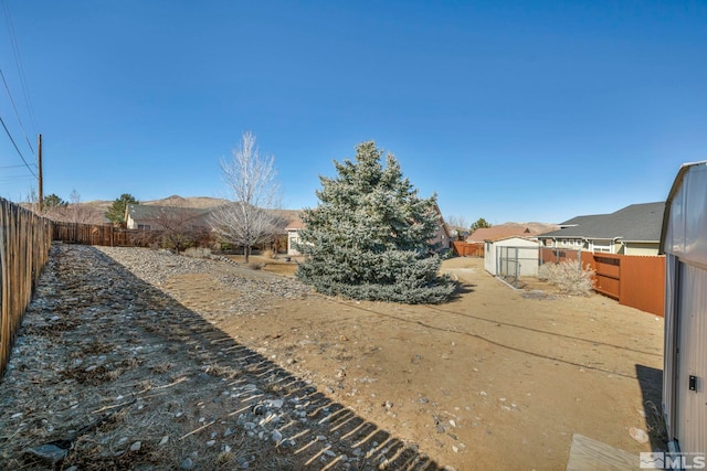 view of yard featuring a storage shed, an outbuilding, and a fenced backyard