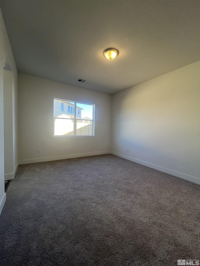 carpeted spare room featuring baseboards, visible vents, and a textured ceiling