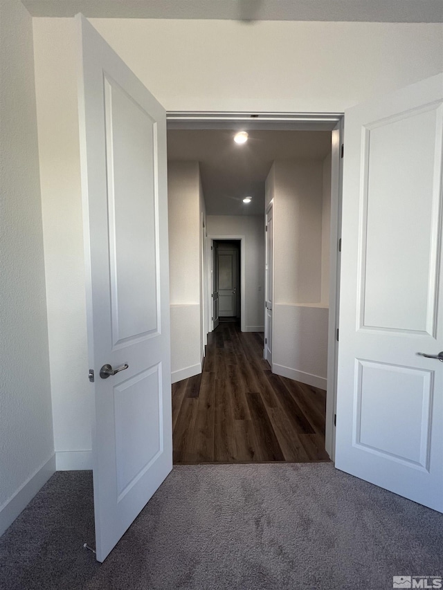 hall featuring baseboards, carpet flooring, and wood finished floors