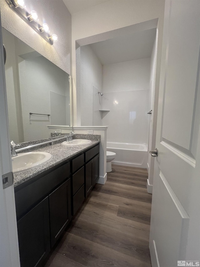 full bath featuring double vanity, wood finished floors, a sink, and toilet