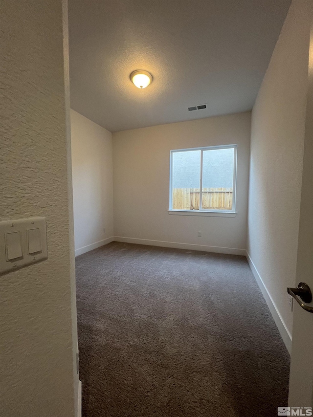 empty room featuring baseboards, visible vents, a textured wall, a textured ceiling, and carpet flooring