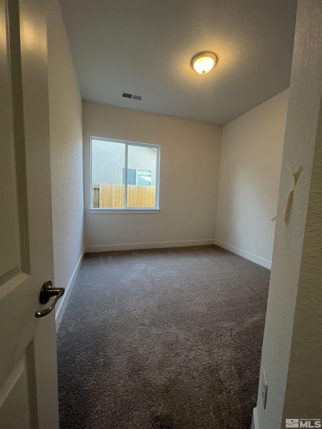 carpeted spare room with a textured ceiling, visible vents, and baseboards