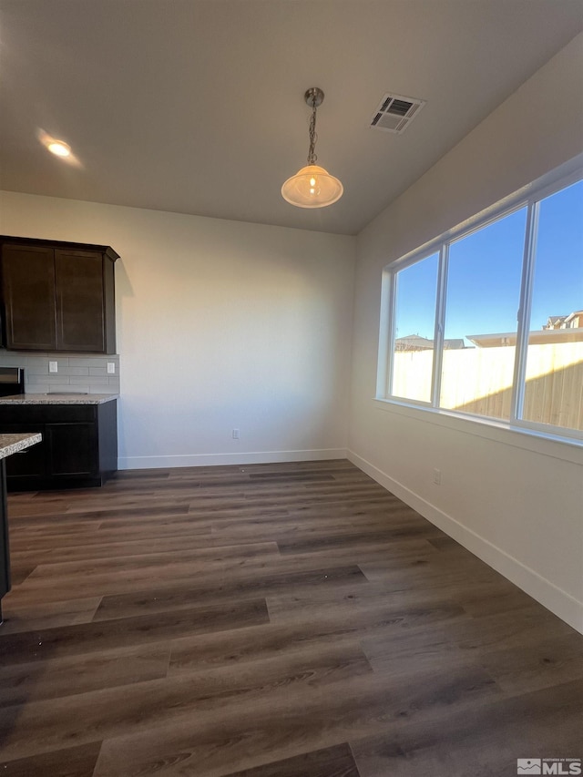 unfurnished dining area with dark wood finished floors, visible vents, and baseboards