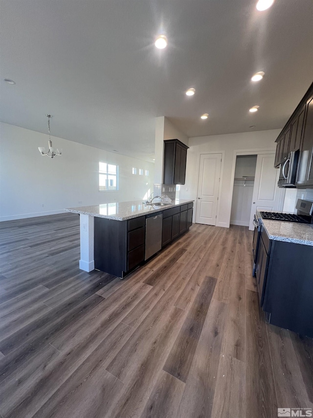 kitchen with baseboards, appliances with stainless steel finishes, dark wood-style flooring, and light stone countertops