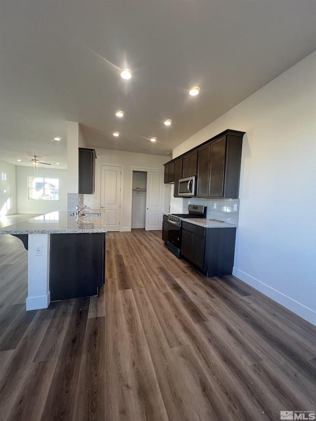 kitchen with appliances with stainless steel finishes, baseboards, dark wood finished floors, and light stone counters