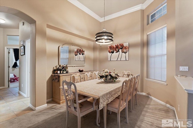 dining room with arched walkways, crown molding, light carpet, and baseboards