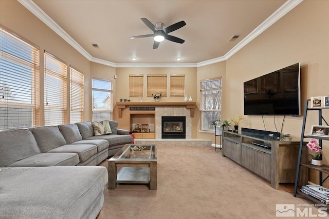 living area with visible vents, ornamental molding, a ceiling fan, carpet flooring, and a tile fireplace