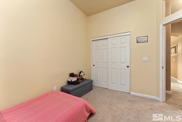 carpeted bedroom featuring a closet and baseboards