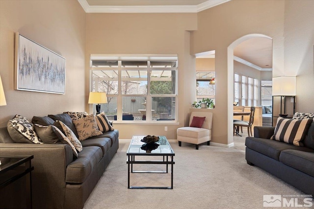 carpeted living room featuring arched walkways, ornamental molding, and baseboards