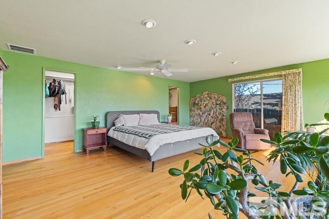 bedroom with a ceiling fan, visible vents, and wood finished floors