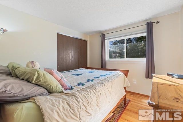 bedroom with a textured ceiling, a closet, and light wood-type flooring