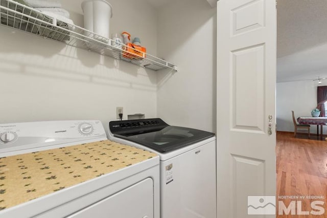 washroom with laundry area, light wood finished floors, and washing machine and clothes dryer