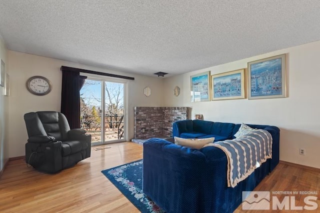 living area with a textured ceiling, baseboards, and wood finished floors