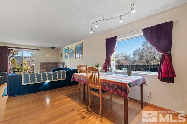 dining room with a textured ceiling, wood finished floors, and track lighting